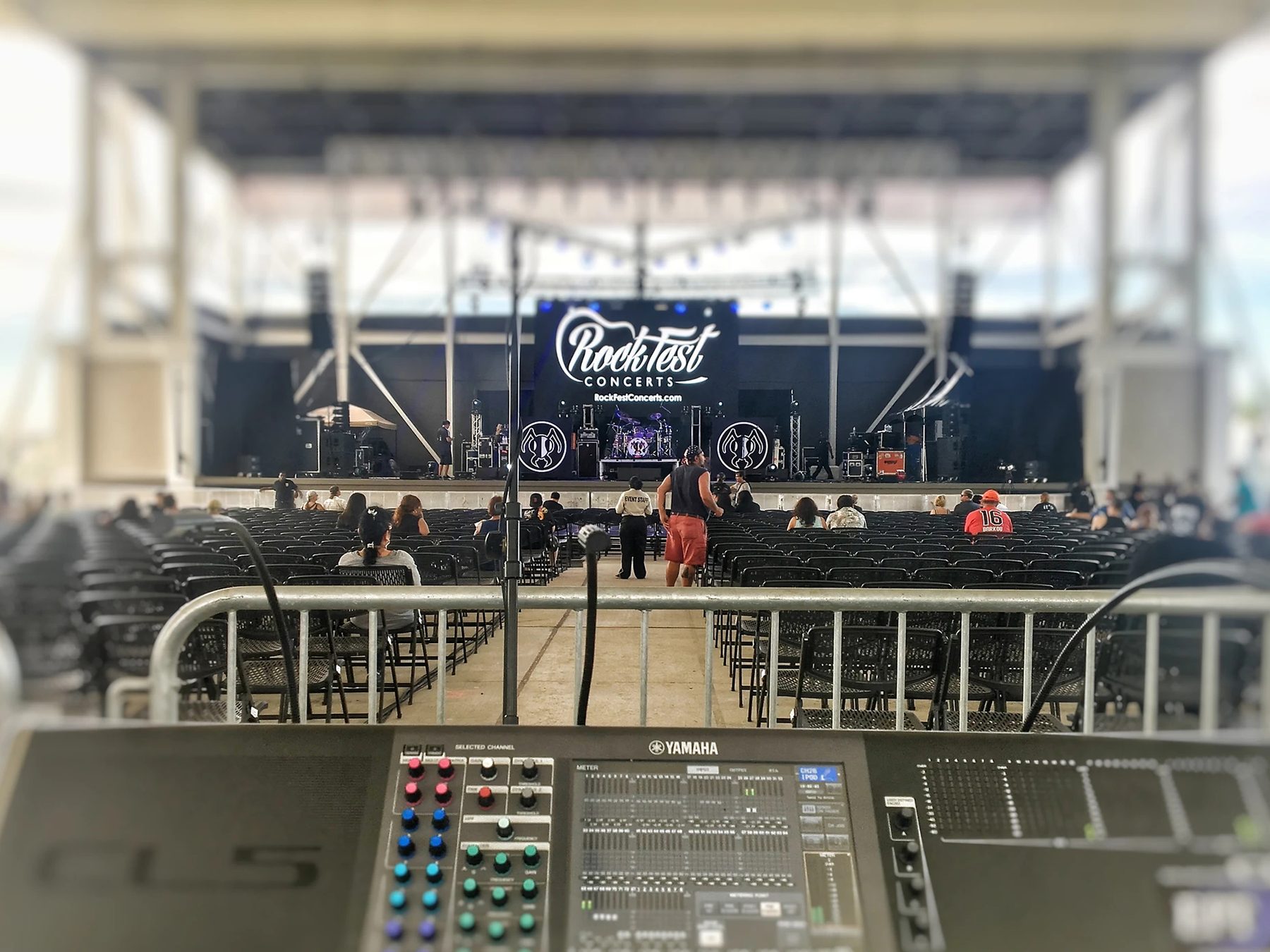Digital audio console at front of house in front of a covered outdoor stage