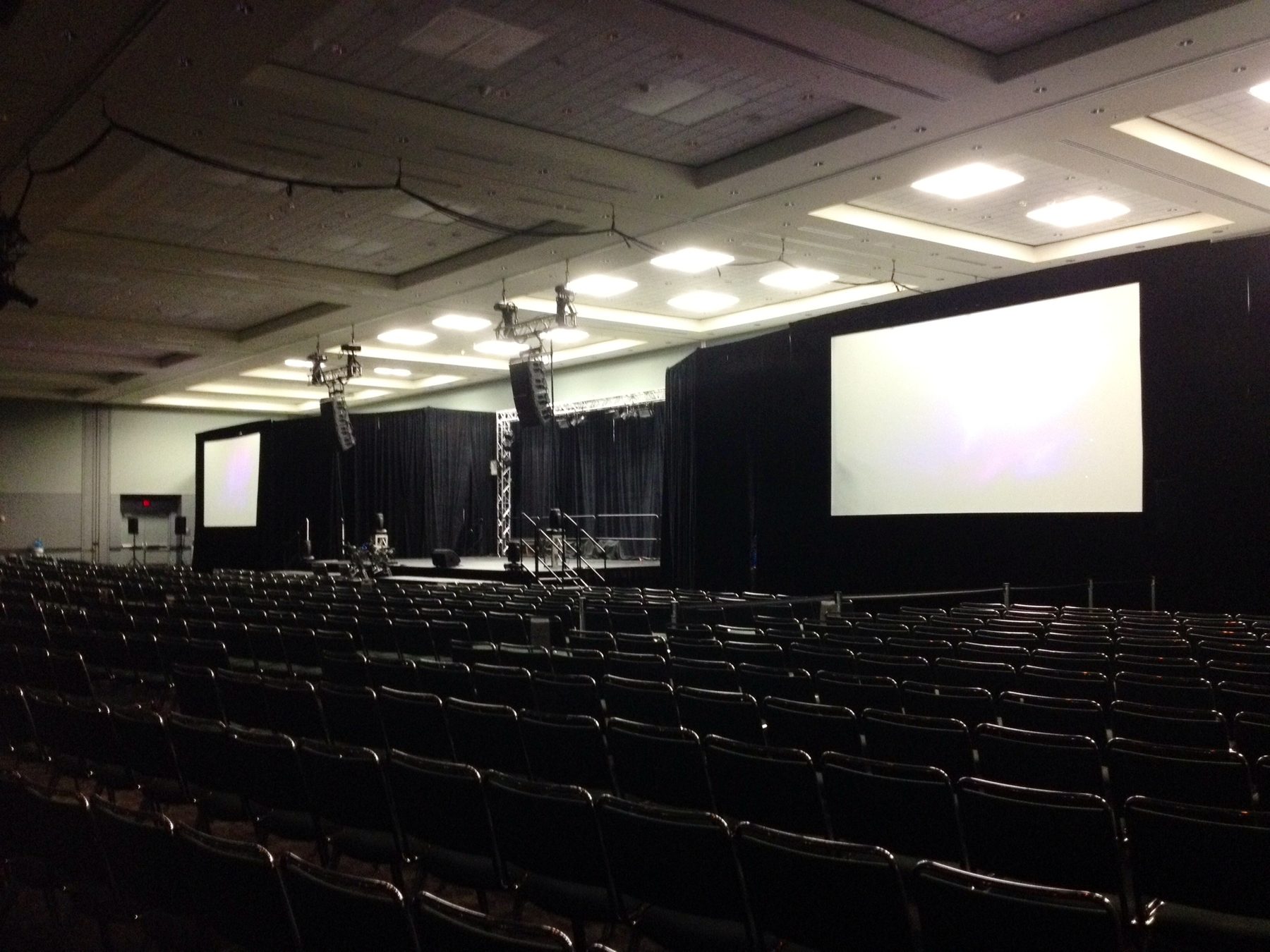 Convention ballroom set with a projection screen, camera position and rows of seating