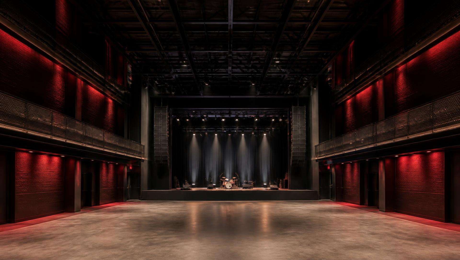 Empty live music venue with black box truss, flown line arrays and installed lighting integrated into the architecture