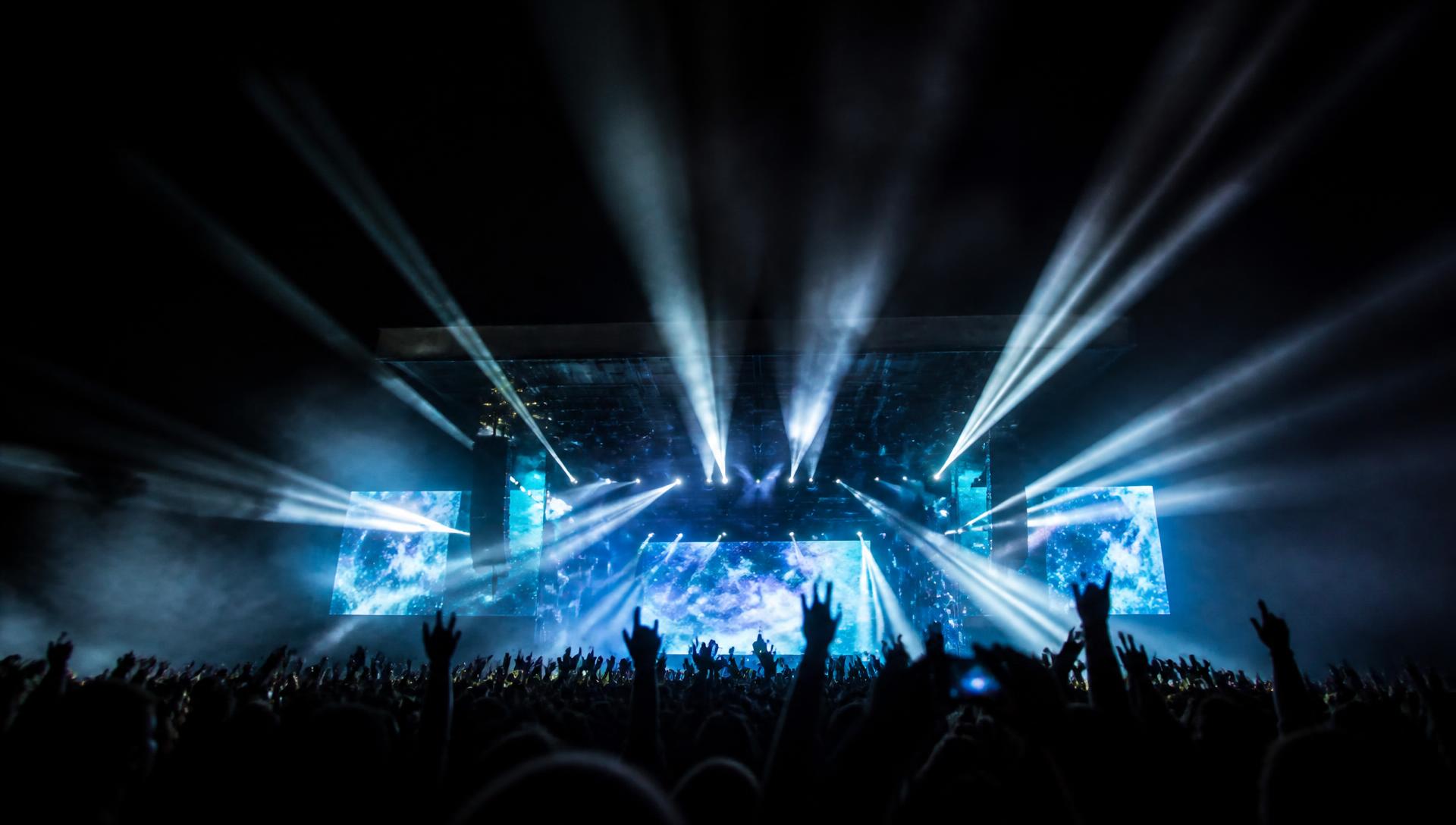 Concert stage at night with beam lighting over a crowd