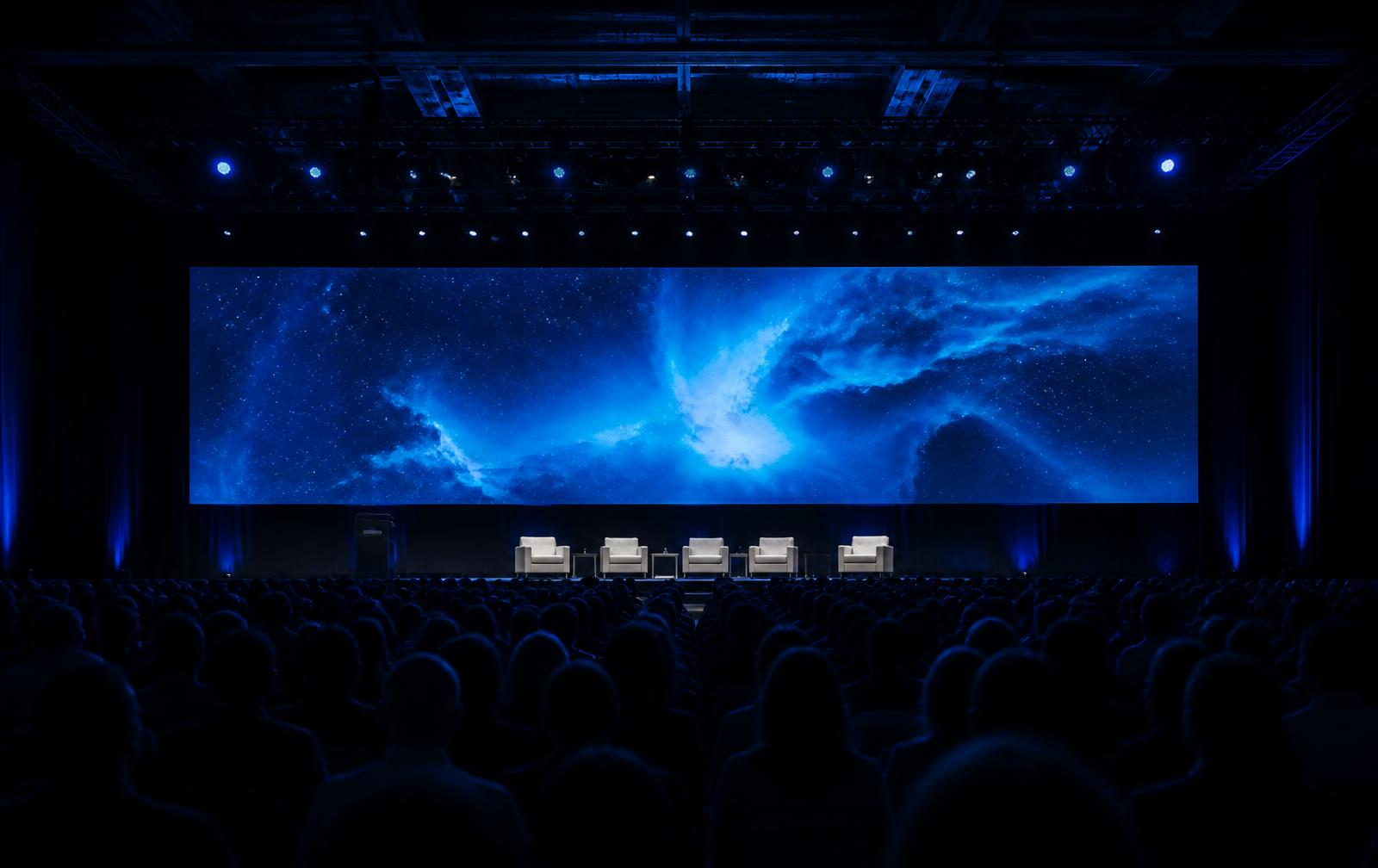 Convention main stage with IMAG screens above a seated audience
